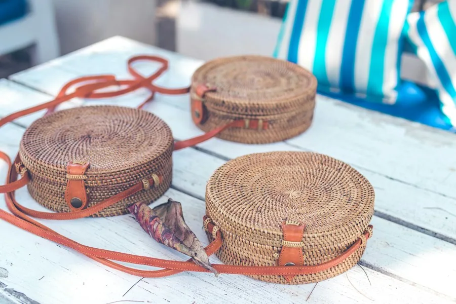 Three round rattan bags with leather straps on a table