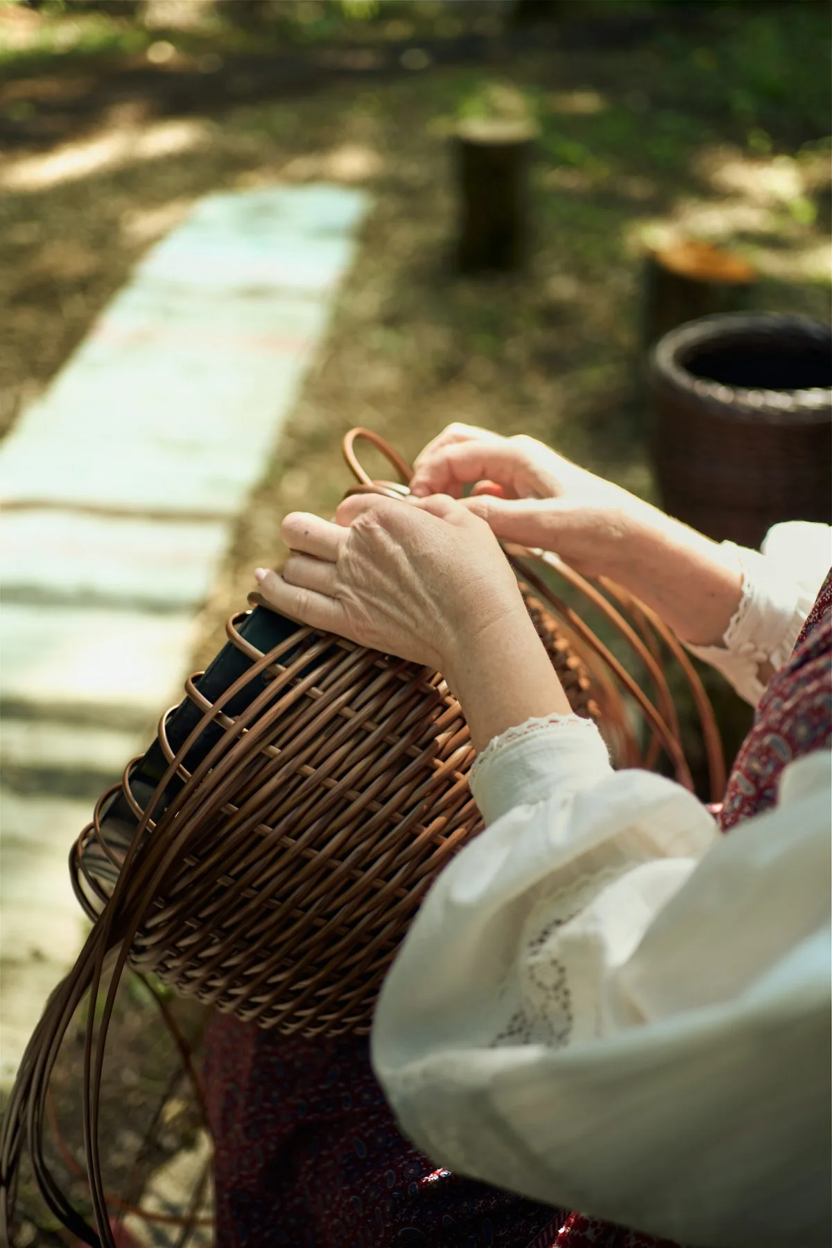 Hands shaping a wicker basket outdoors