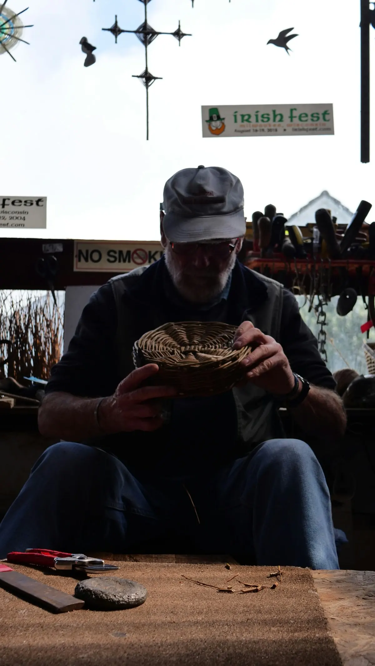 Craftsman weaving a small wicker basket at his bench