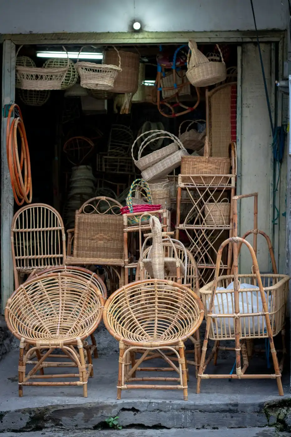Rattan chairs and woven baskets stacked outside an Indonesian craft shop