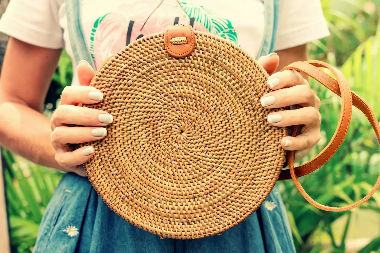 Hands holding a handwoven round Bali rattan bag
