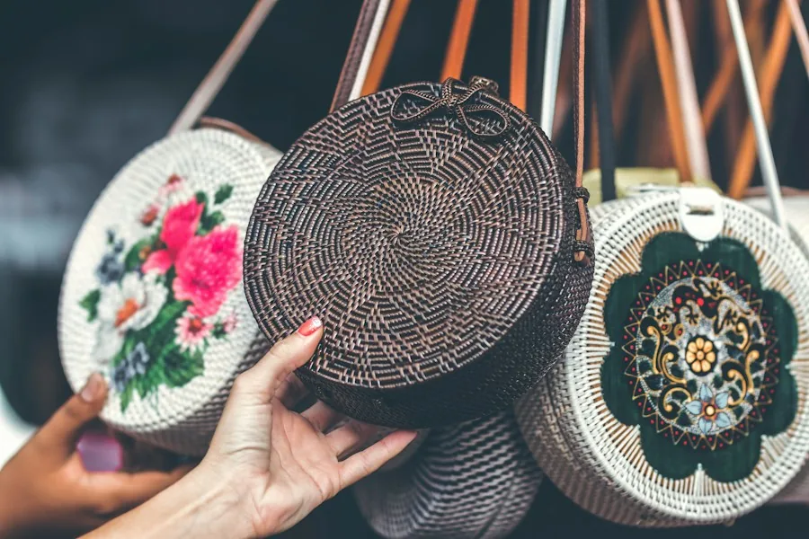 Hands holding round woven rattan bags with painted and natural fronts