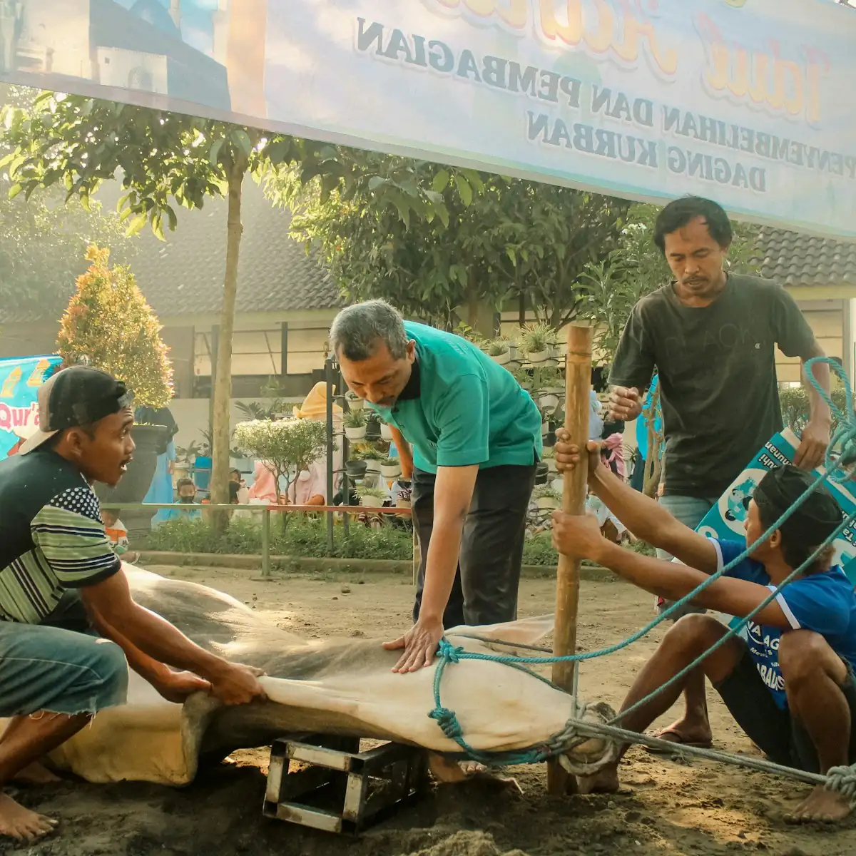 Group of Indonesian craftsmen working on a wooden piece outdoors