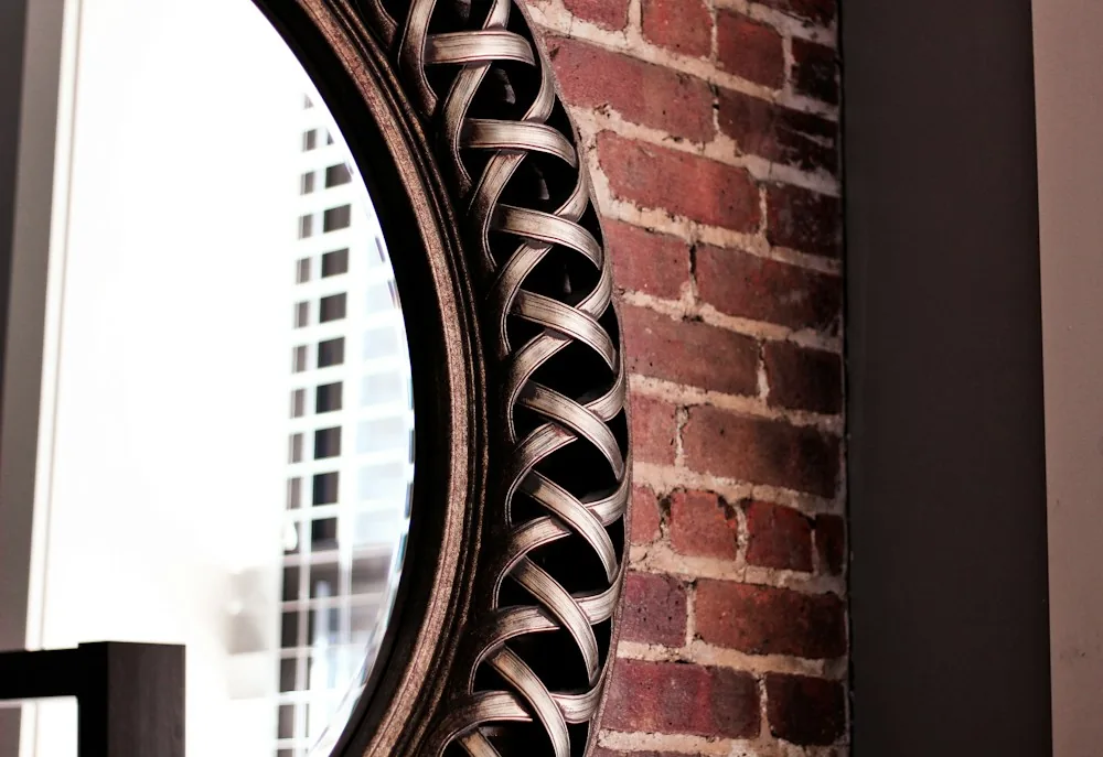 Round woven-frame rattan mirror on a brick wall