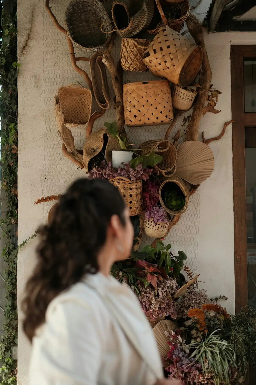Woman looking at a wall decorated with woven baskets