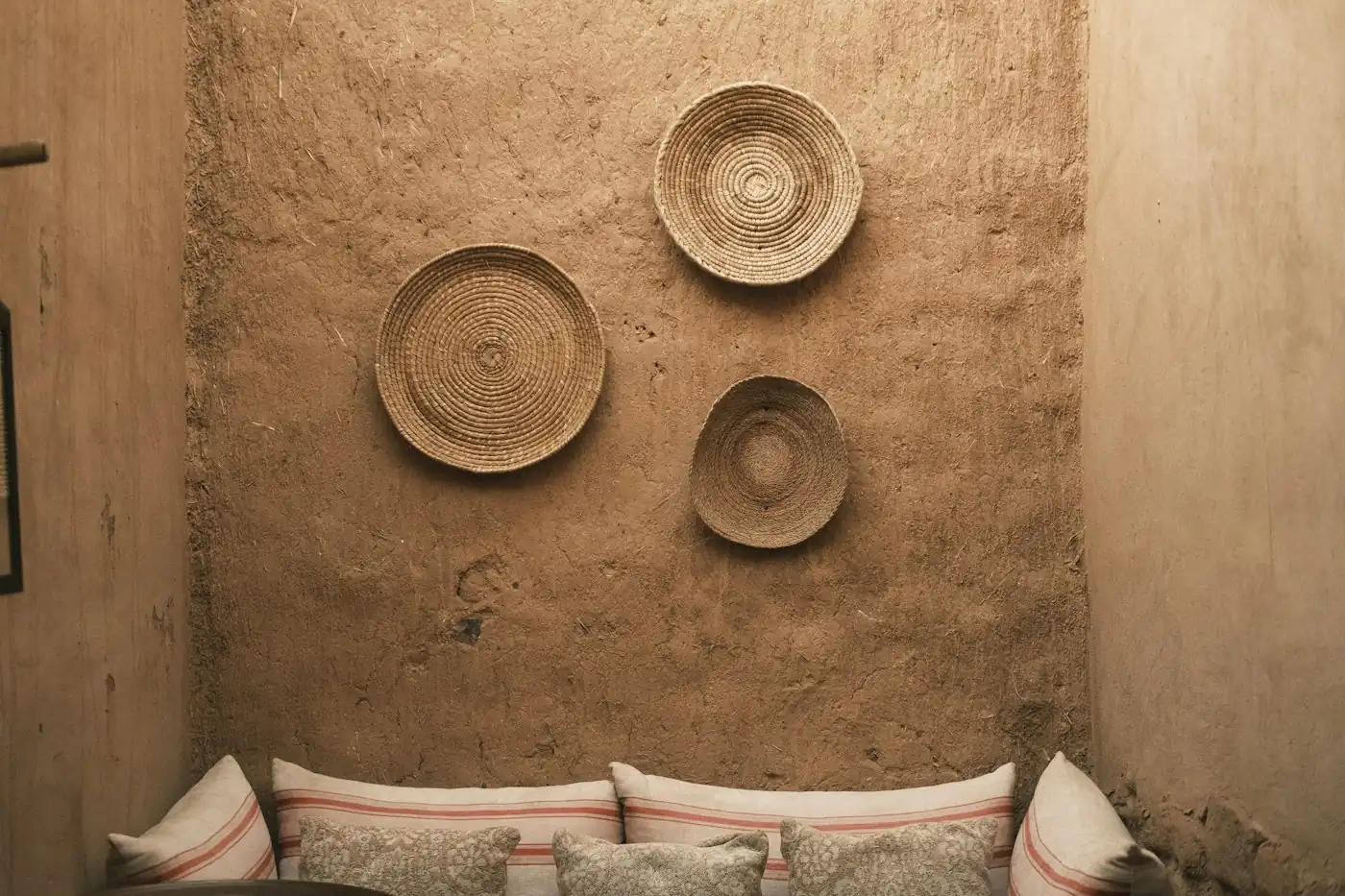 Woven rattan plates hung as wall décor above cushions