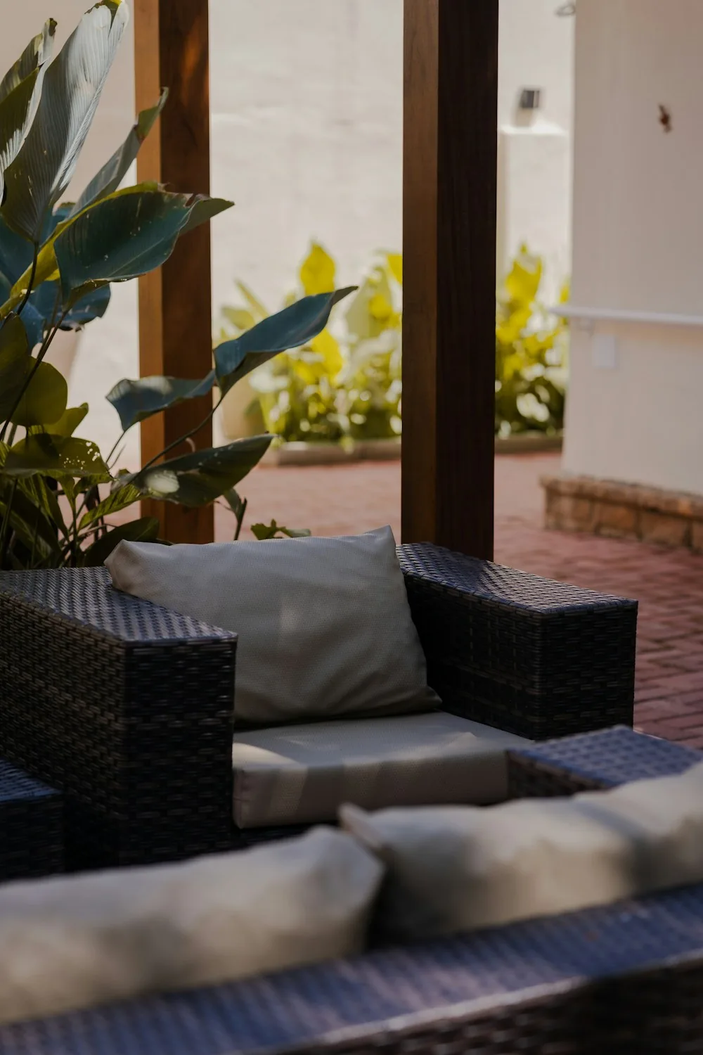 Dark wicker armchair with a cushion on a brick patio