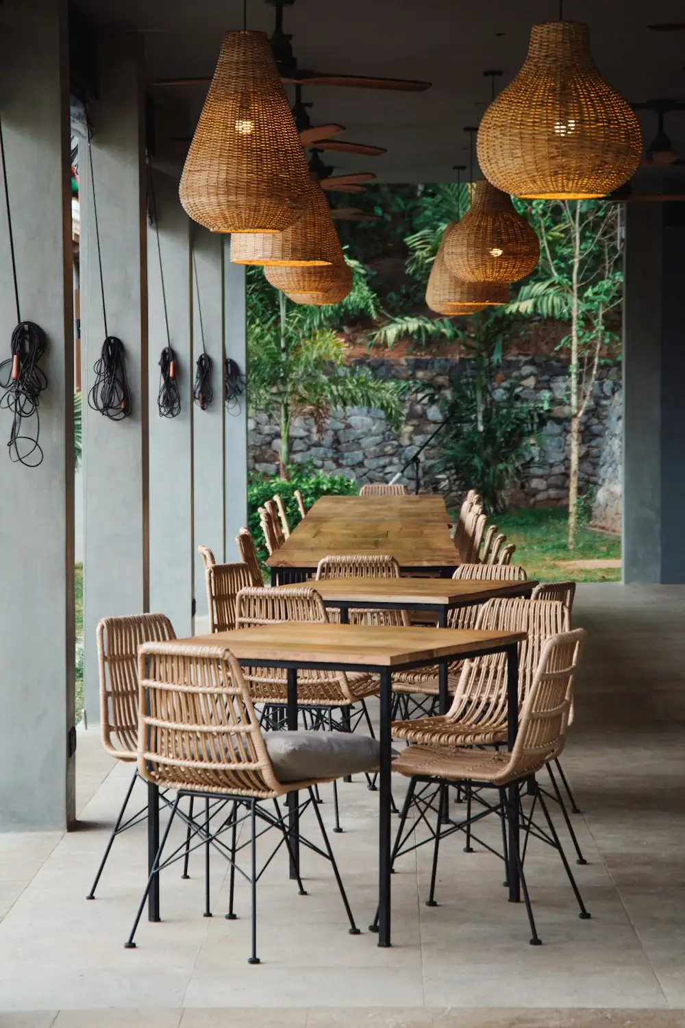 Café furnished with rattan chairs, tables and woven pendant lamps