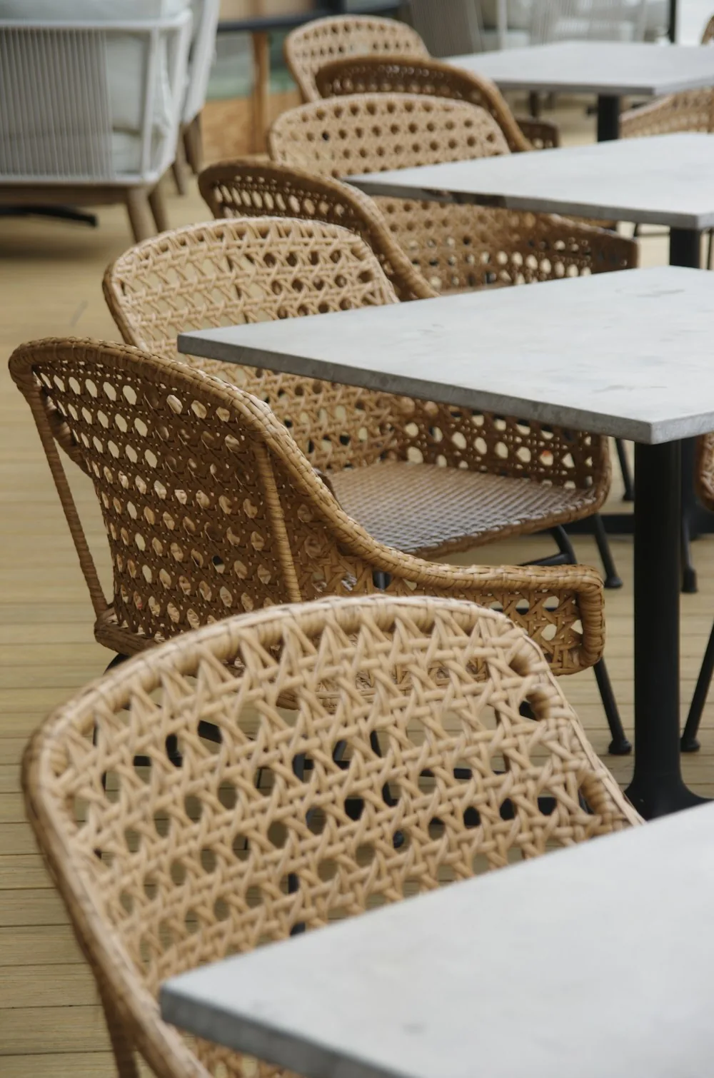Woven rattan dining chairs at square tables on an outdoor terrace