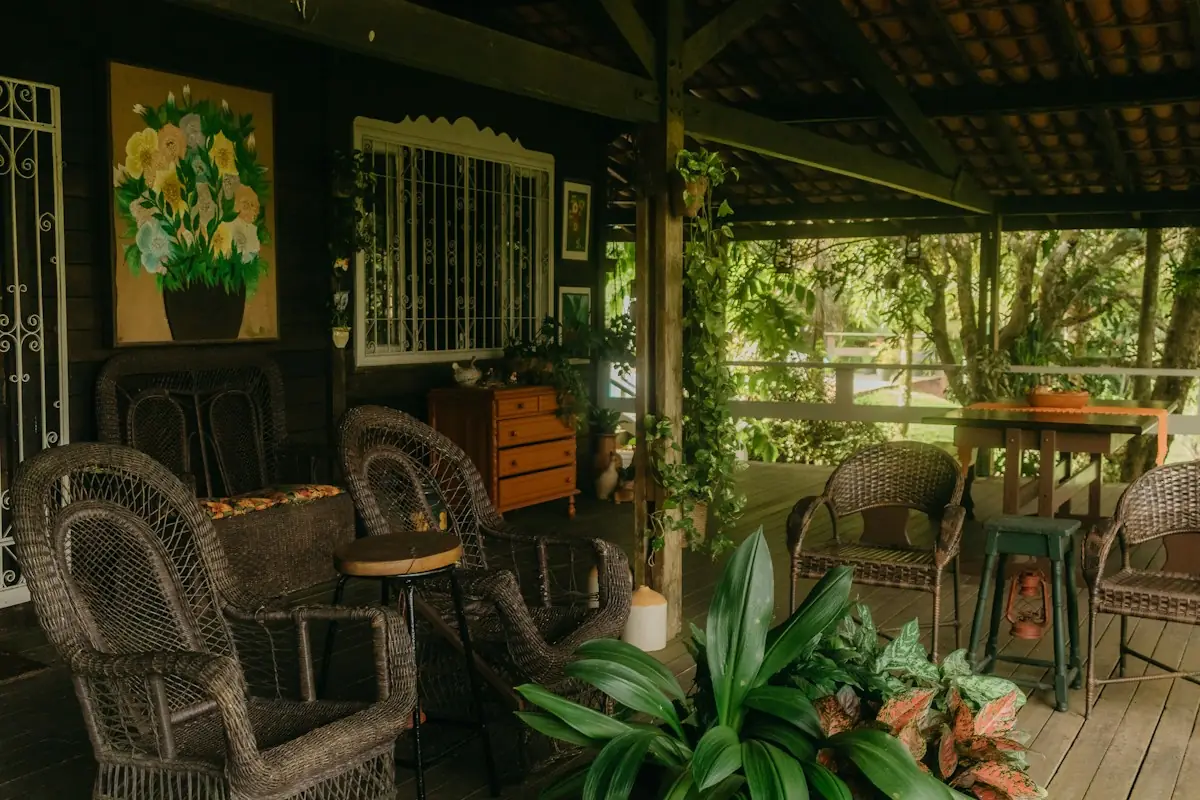 Porch furnished with wicker chairs among tropical plants