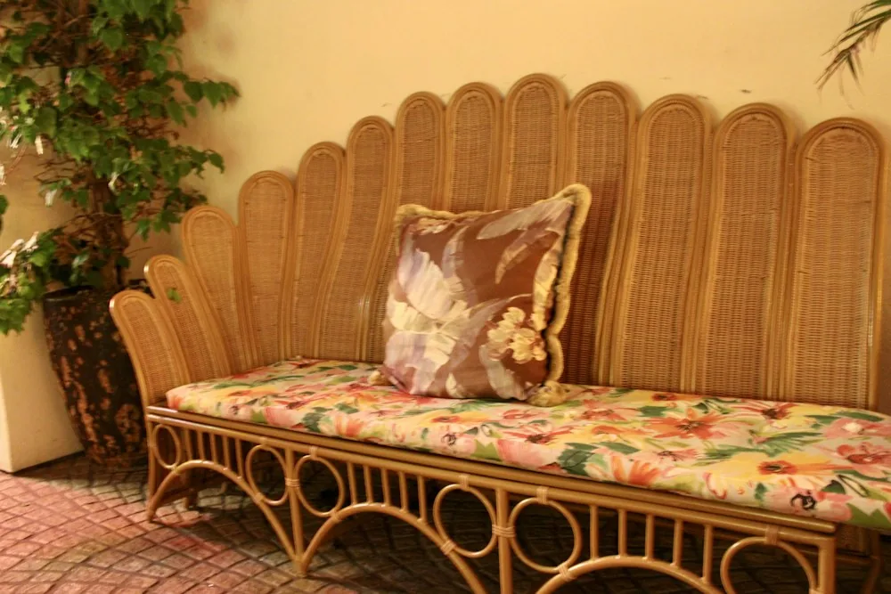 Rattan sofa with a scalloped back and floral cushions